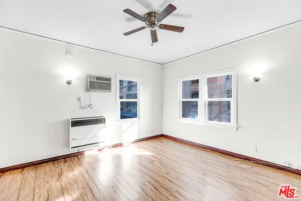 a view of empty room with wooden floor and fan
