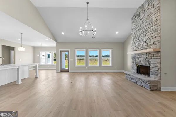 an empty room with wooden floor fireplace and windows