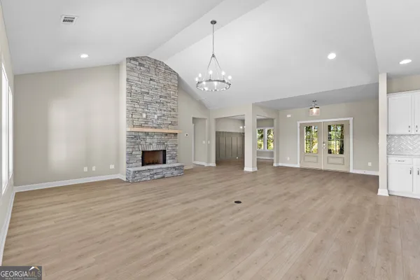 an empty room with wooden floor fireplace and window