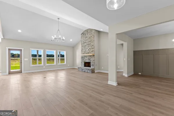 an empty room with wooden floor chandelier and windows