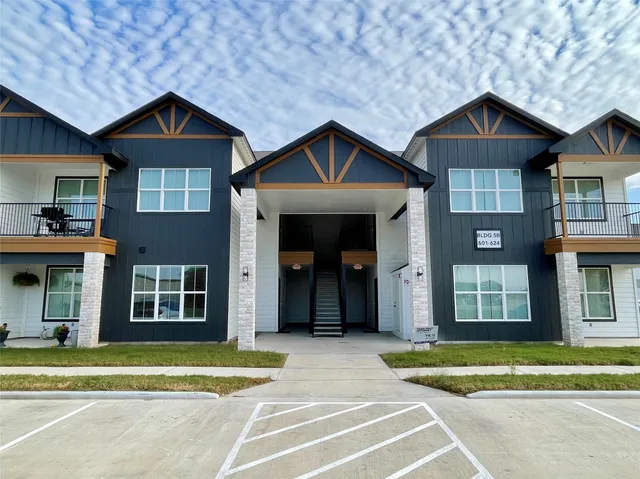 a view of a brick house with a yard plants and large trees