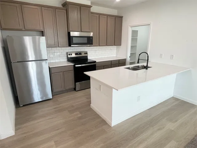 a kitchen with appliances a sink and a refrigerator