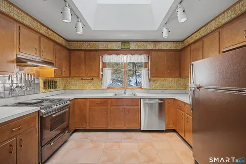 a kitchen with stainless steel appliances granite countertop a refrigerator a sink dishwasher a stove and white countertops with cabinets