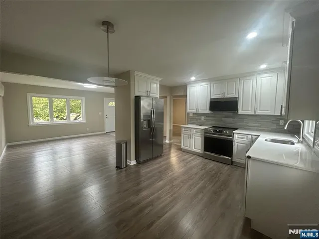 a kitchen with stainless steel appliances granite countertop a refrigerator a sink dishwasher a stove and a wooden floors