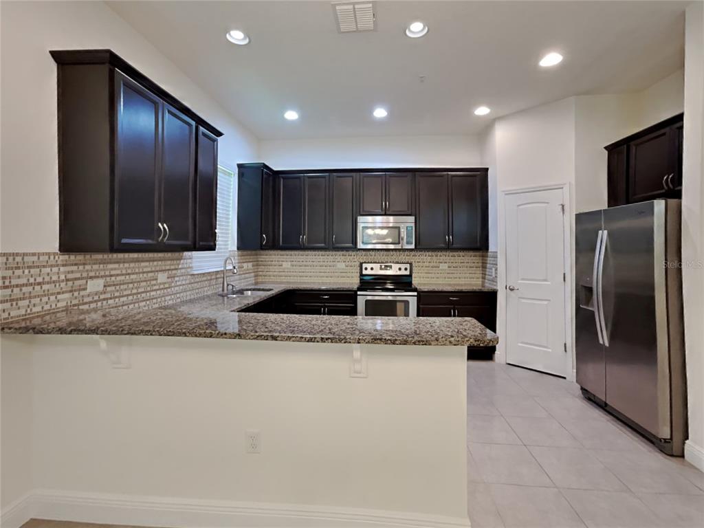 8326 Bryce Canyon Avenue Windermere, FL 34786 - Photo 6 of 20 a large kitchen with stainless steel appliances granite countertop a refrigerator a oven a sink and a granite counter tops