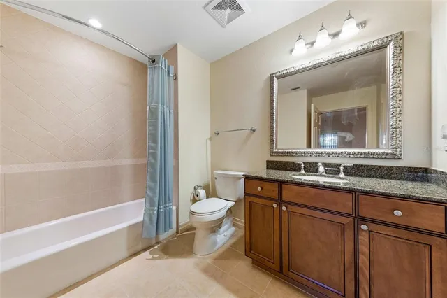 a bathroom with a granite countertop sink mirror vanity bathtub and a toilet