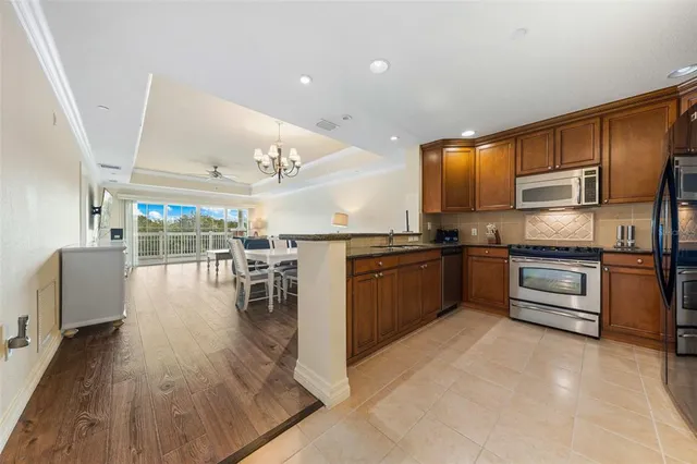 a kitchen with stainless steel appliances kitchen island granite countertop a refrigerator a stove a sink a dining table and chairs with wooden floor