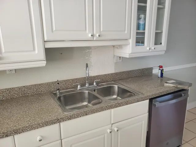 a kitchen with granite countertop white cabinets and a sink