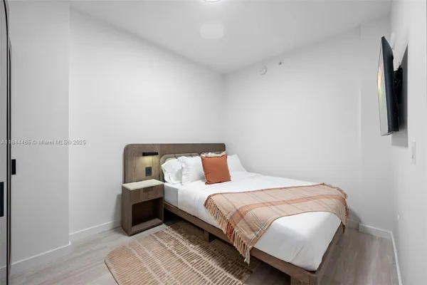 a bedroom with a bed a flat screen tv and dresser