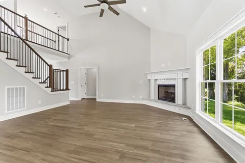 a view of an empty room with wooden floor fireplace and a window
