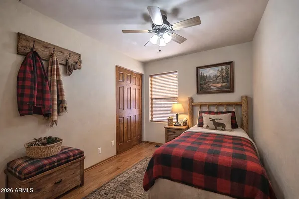 an empty room with wooden floor chandelier fan and windows