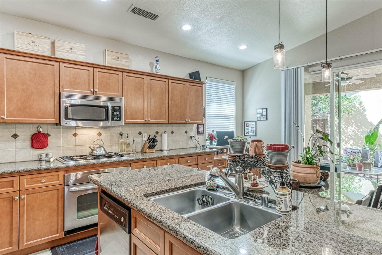 3754 Salem Lane Clovis, CA 93619 - Photo 7 of 18 a kitchen with granite countertop a sink a counter top space appliances and cabinets