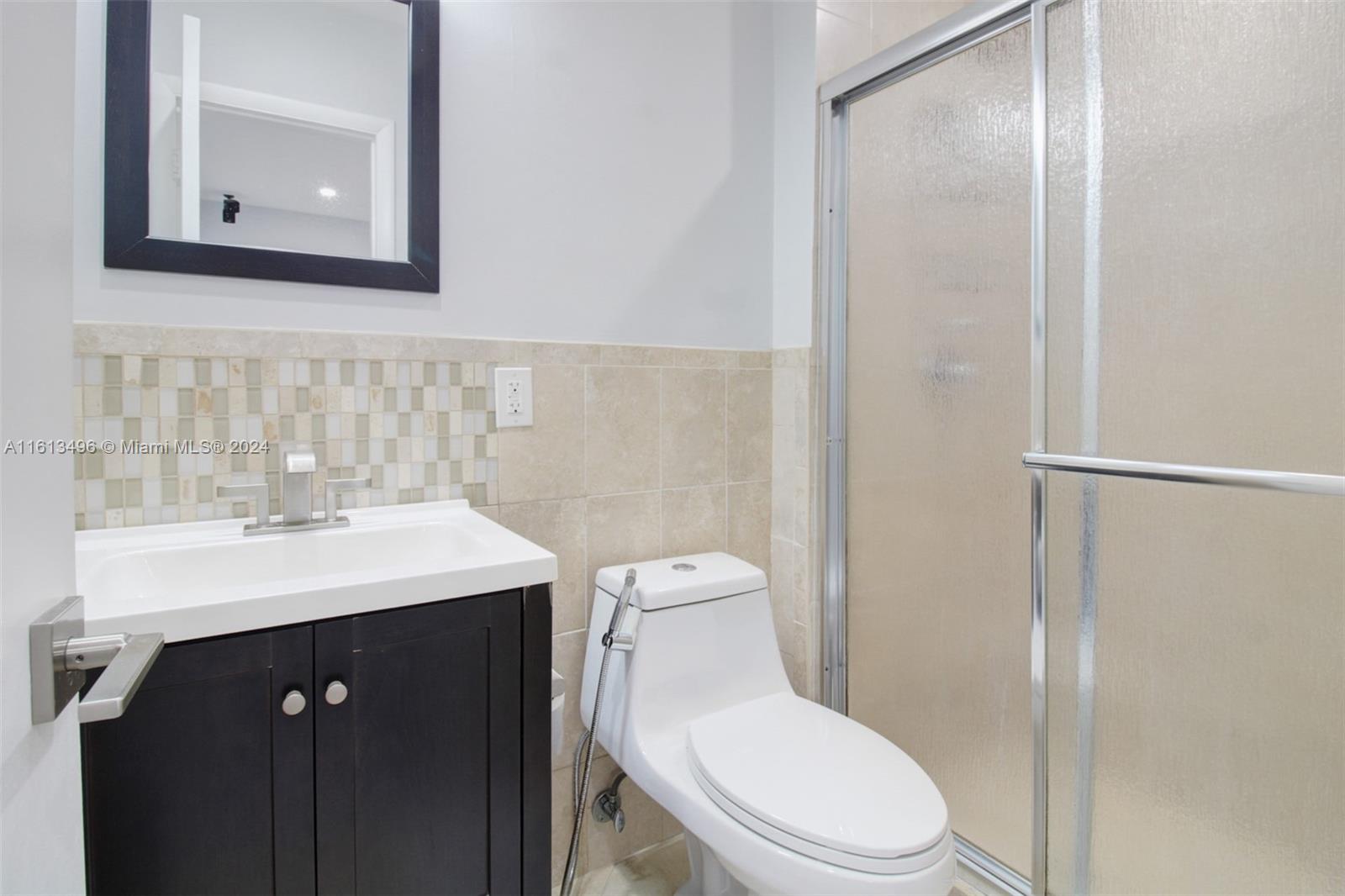 9730 Southwest 76th Street Miami, FL 33173 - Photo 13 of 27 a bathroom with a toilet a sink a mirror and vanity