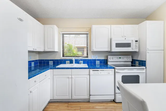 a kitchen with granite countertop white cabinets and white appliances