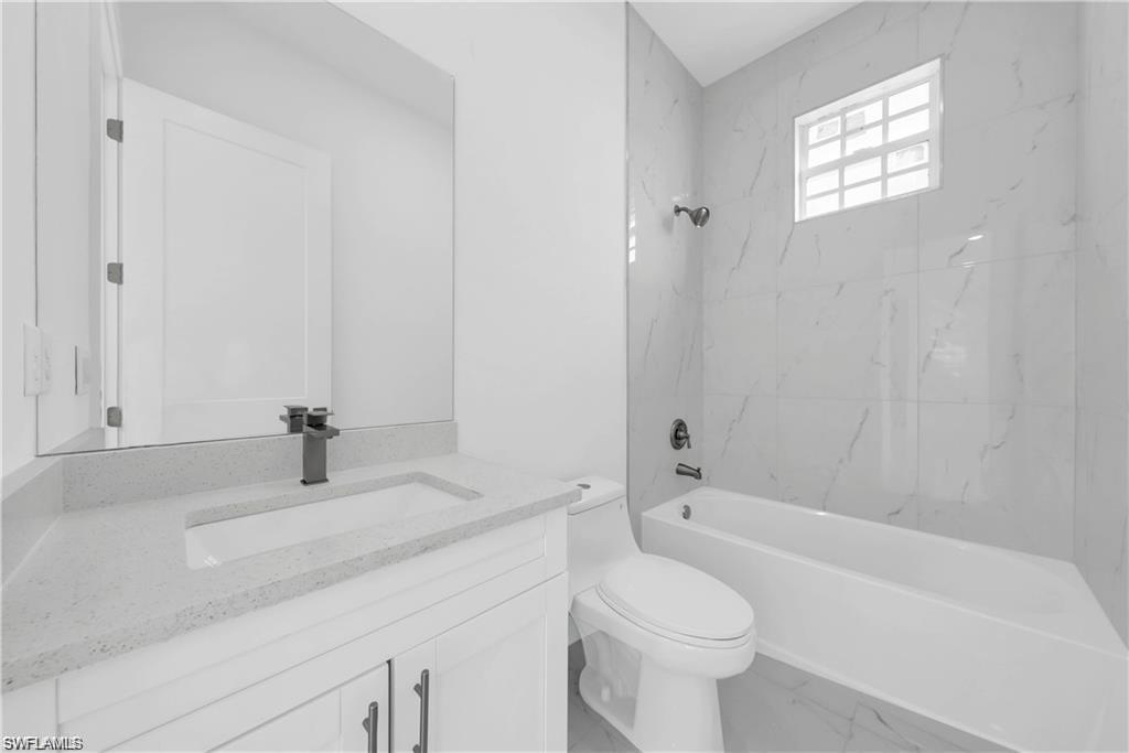 3310 11th Street West Lehigh Acres, FL 33971 - Photo 12 of 20 a bathroom with a granite countertop toilet a sink and a bathtub