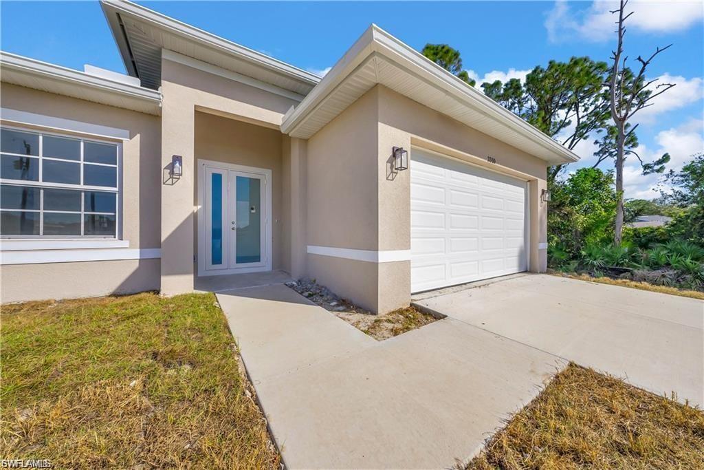 3310 11th Street West Lehigh Acres, FL 33971 - Photo 3 of 20 a front view of a house with a yard and garage