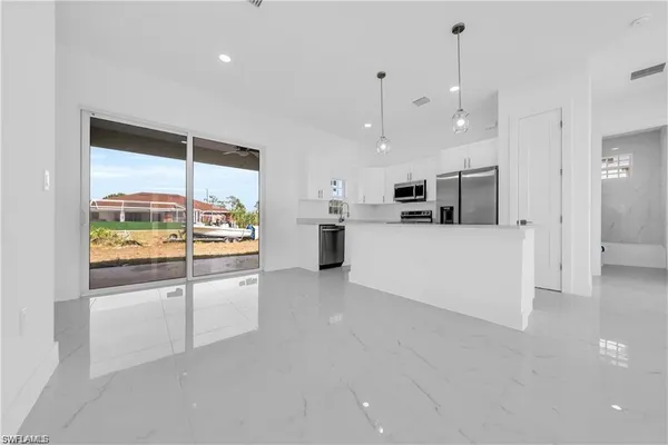 a large white kitchen with a large window and stainless steel appliances