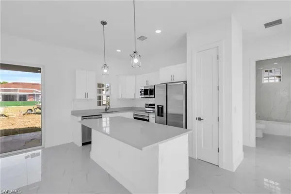 a kitchen with stainless steel appliances granite countertop a refrigerator a stove and a sink