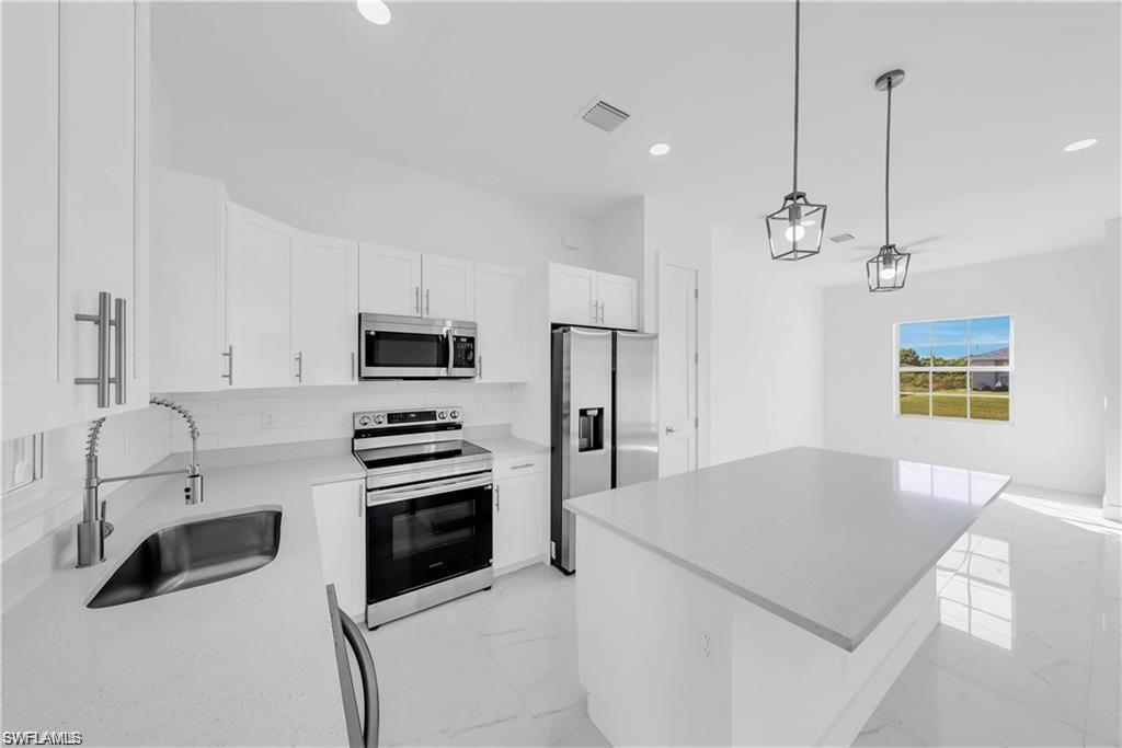3310 11th Street West Lehigh Acres, FL 33971 - Photo 7 of 20 a kitchen with stainless steel appliances a stove a sink island and a refrigerator