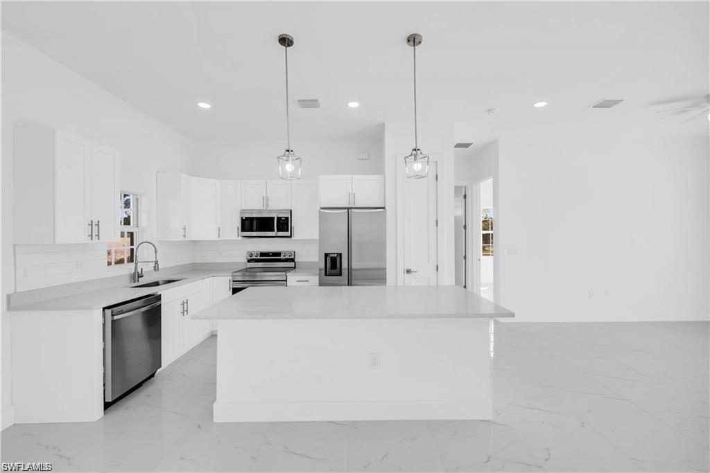 3310 11th Street West Lehigh Acres, FL 33971 - Photo 8 of 20 a large kitchen with stainless steel appliances kitchen island a large counter top and a sink