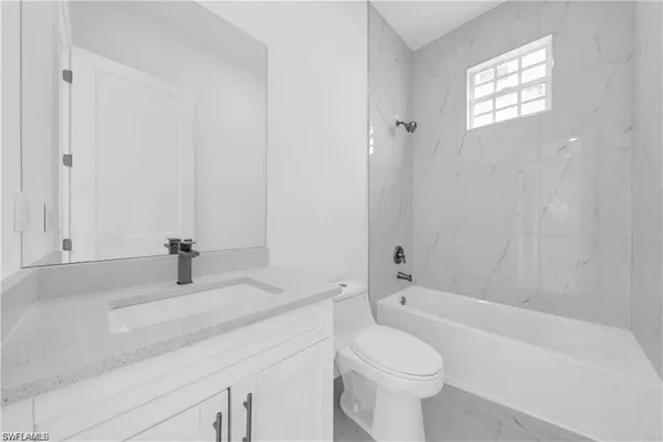 a bathroom with a granite countertop toilet a sink and a bathtub