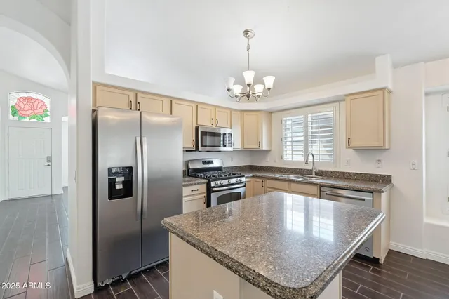an empty room with wooden floor chandelier fan and windows
