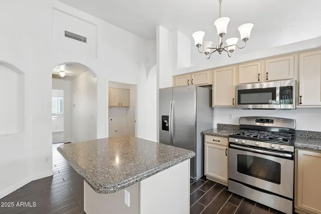 a kitchen with stainless steel appliances granite countertop a refrigerator a sink dishwasher a stove and a refrigerator with wooden floor