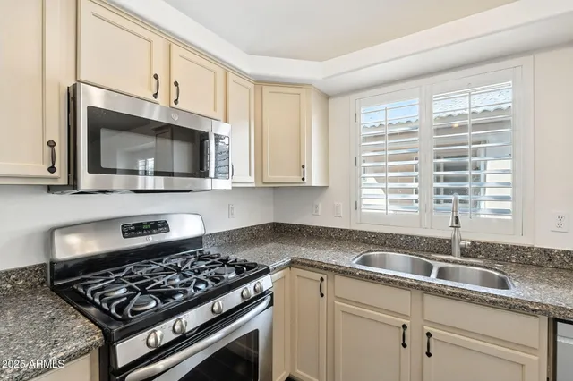 a kitchen with stainless steel appliances granite countertop a sink a stove oven a refrigerator with a dining table and chairs