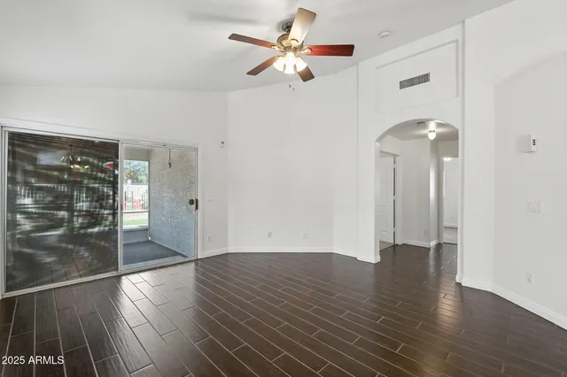 a view of empty room with wooden floor and fan