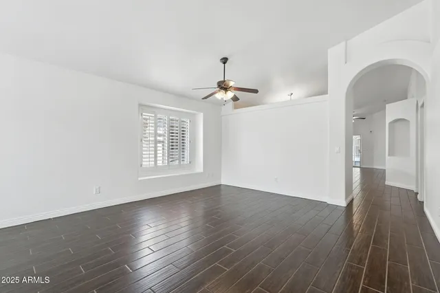 an empty room with wooden floor ceiling fan and windows