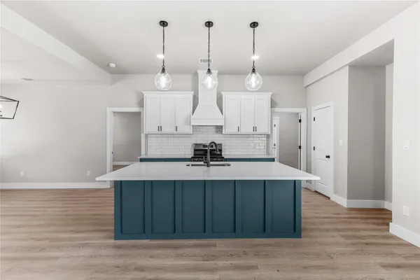 a view of a kitchen with kitchen island a sink wooden floor and a chandelier