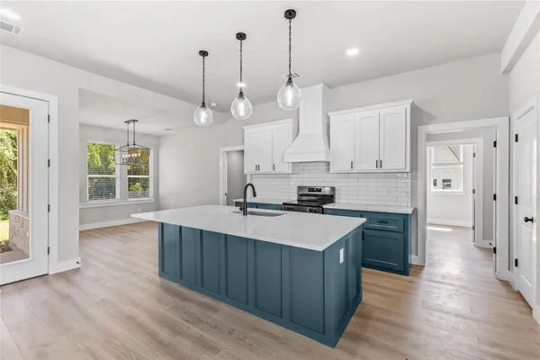 a large kitchen with stainless steel appliances a large counter top a sink a refrigerator and a window