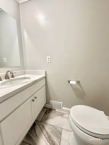 a bathroom with a granite countertop toilet and a sink