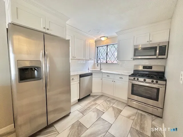 a kitchen with stainless steel appliances a refrigerator sink and microwave