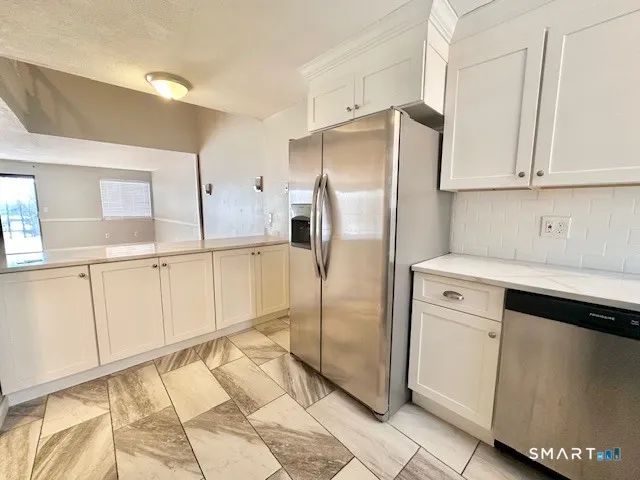 a kitchen with white cabinets a refrigerator and a sink