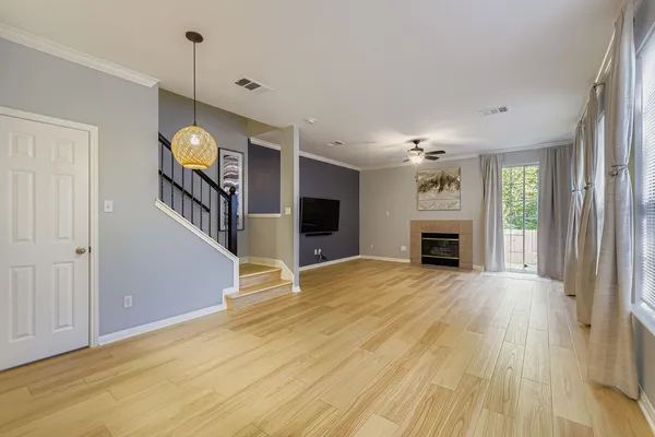 a view of an empty room with wooden floor fireplace and a window