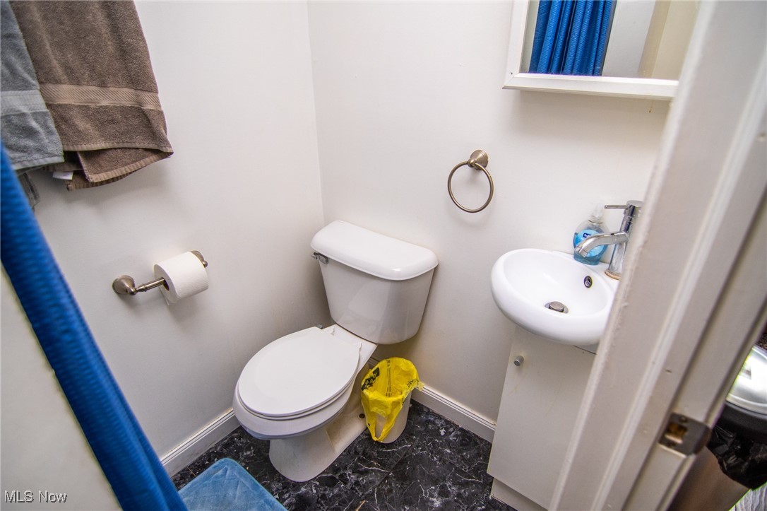 55577 National Road Bridgeport, OH 43912 - Photo 12 of 17 Half bathroom with toilet, marble finish floor, baseboards, and a sink