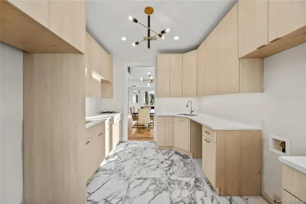 a large white kitchen with granite countertop a sink and dishwasher a stove with wooden floor