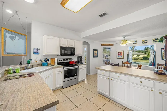 a open kitchen with stainless steel appliances granite countertop a stove top oven a sink dishwasher and white cabinets with wooden floor