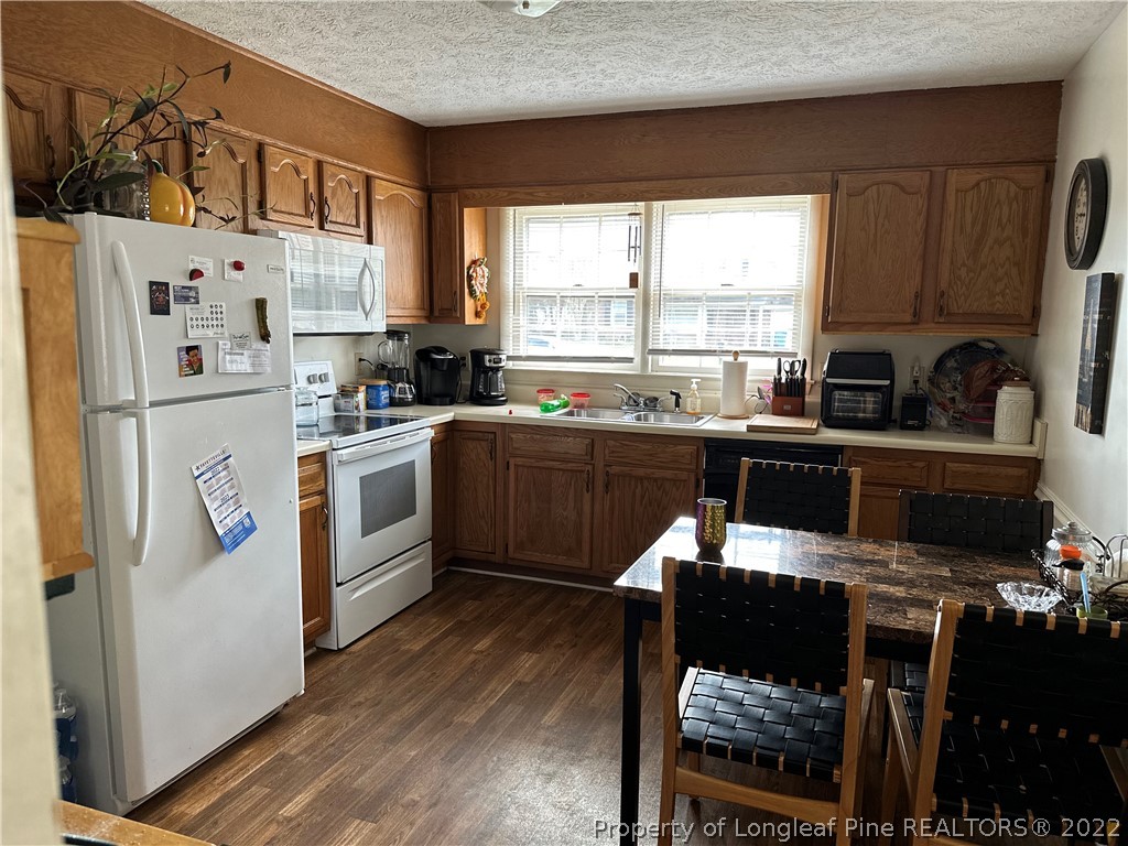 7405 Southgate Road Fayetteville, NC 28314 - Photo 6 of 16 a kitchen with stainless steel appliances a stove a sink dishwasher a refrigerator white cabinets and wooden floor