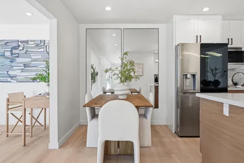 a kitchen with kitchen island a dining table chairs stainless steel appliances and cabinets