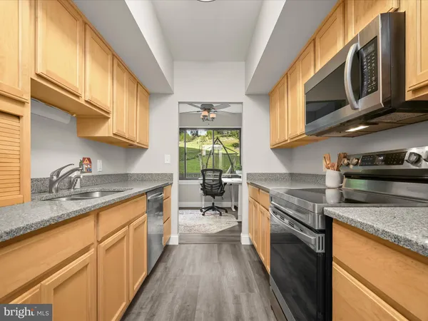 a kitchen with stainless steel appliances granite countertop wooden cabinets granite counter tops and a window