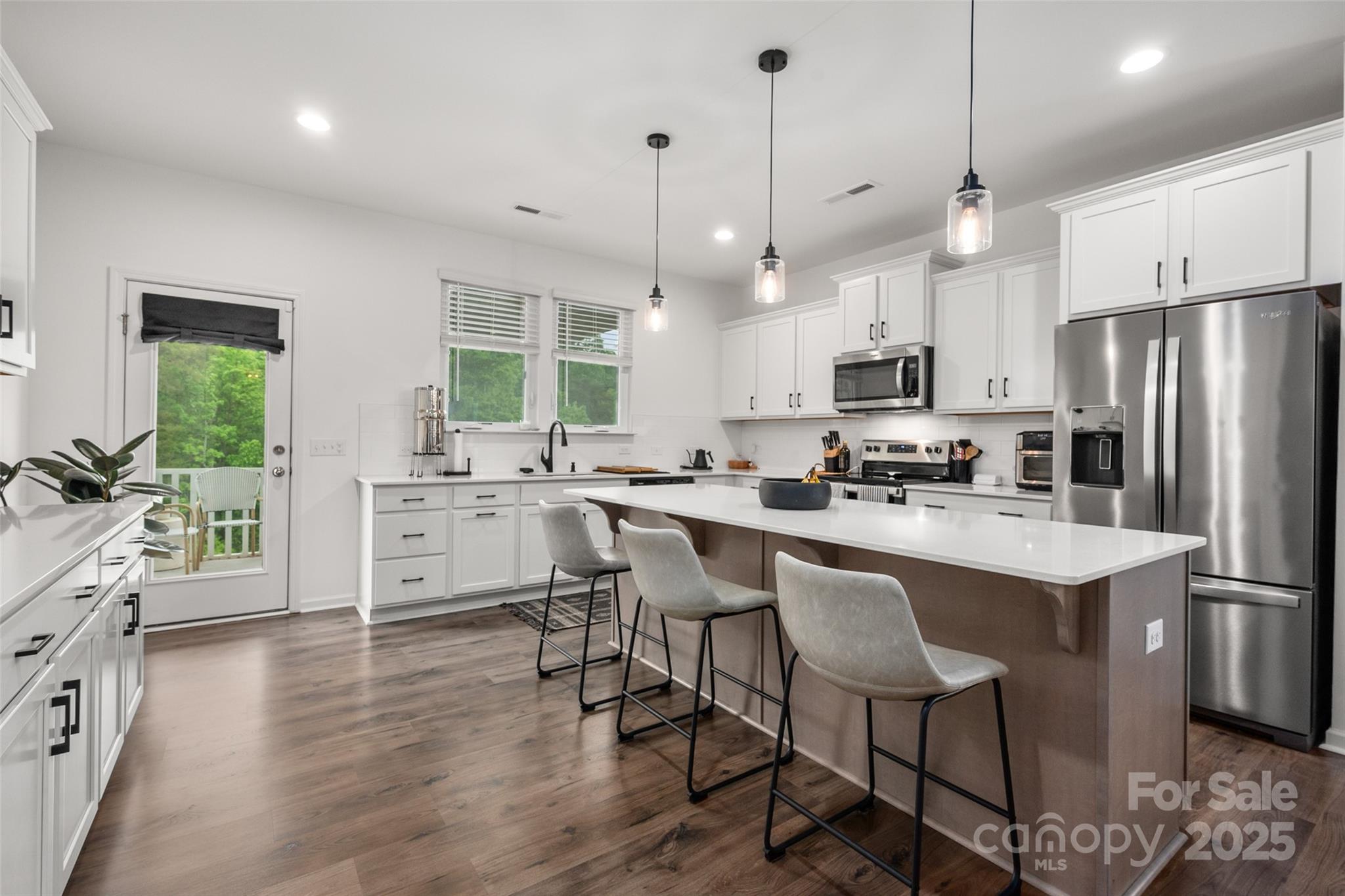 1024 Scotch Meadows Loop, Unit 32 Monroe, NC 28110 - Photo 7 of 19 a kitchen with stainless steel appliances kitchen island a large white table chairs and a refrigerator