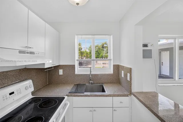 a kitchen with a sink a stove cabinets and a window
