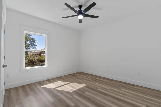 an empty room with a window and a ceiling fan