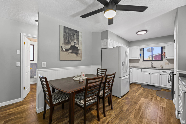 5896 South 3950th Street West Roy, UT 84067 - Photo 6 of 29 Dining space with a textured ceiling, a wainscoted wall, dark wood-type flooring, and a ceiling fan