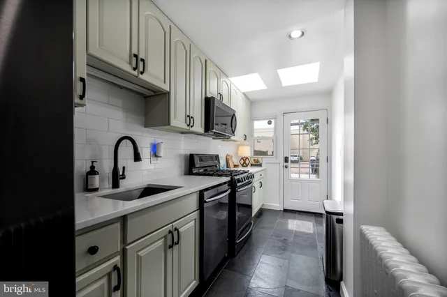 a kitchen with stainless steel appliances granite countertop a sink stove refrigerator and cabinets