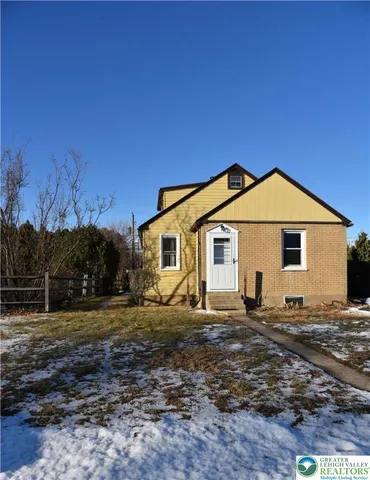 a view of a white house next to a yard with trees