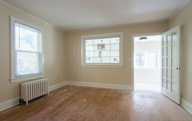 a view of an empty room with wooden floor and a window