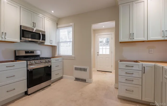 a kitchen with stainless steel appliances granite countertop white cabinets and window